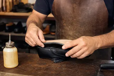 Profissional colando a sola de um sapato em ambiente de sapateiro.